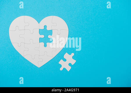 White Puzzle Heart Shape With Missing Piece, On Blue Stock Photo