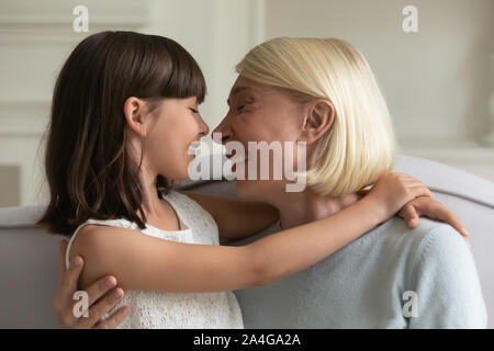Happy middle aged granny touching noses with cute little granddaughter. Stock Photo