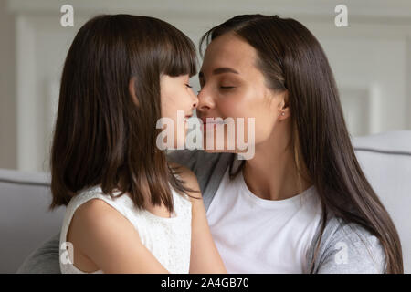 Cute preschool little girl touching noses with affectionate young mother. Stock Photo