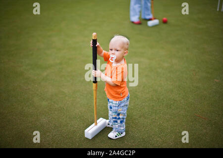 Male toddler attempting to play croquet Stock Photo