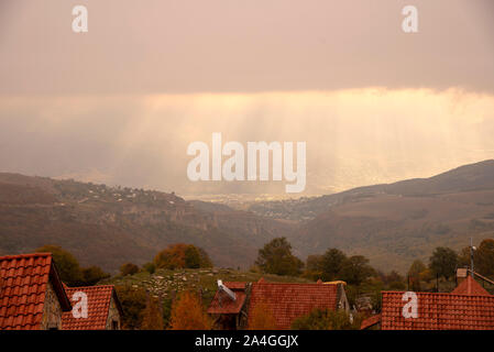The sun's rays through the clouds illuminate the tiled roofs  Stock Photo