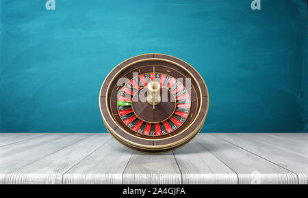 3d rendering of a casino roulette stands on its side on a wooden desk in front of a blue background. Stock Photo