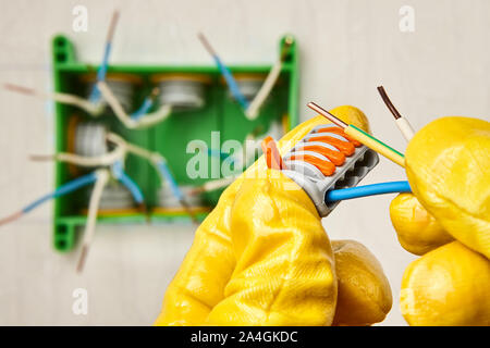 Cable or wire connector terminal block with spring lever for connecting electrical conductor. An electrician installs a junction box in an office buil Stock Photo