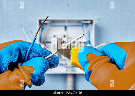 The use of a construction knife when installing a switchboard in a residential building, removing insulation from the end of a copper wire. Home elect Stock Photo