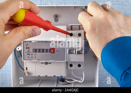 An electrician installs of electrical panel with circuit breakers and an electricity meters in a household electrical network. Wiring of the distribut Stock Photo