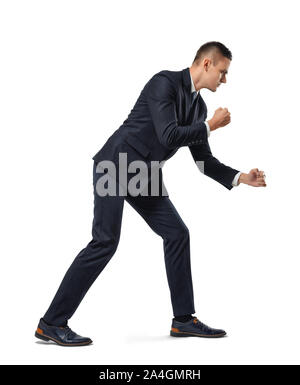 Young businessman posing like he is pulling rope over his shoulder isolated on white background Stock Photo
