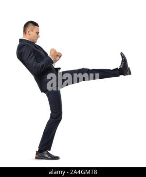 Young businessman kicking someone or something isolated on a white background Stock Photo