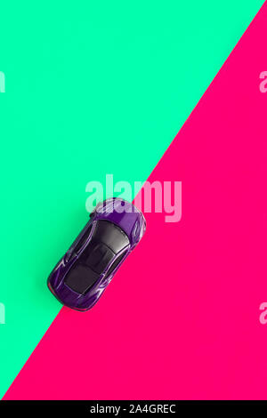 Moscow, Russia - 30 September, 2019. Kids toy car on trendy colorful background. Baby car top view on green and pink colored paper. Boys game. Travel and sport lifestyle. Business, transportation concept Stock Photo