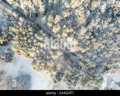 Beautiful aerial view of snow covered pine forests and a road winding among trees. Rime ice and hoar frost covering trees. Scenic winter landscape nea Stock Photo