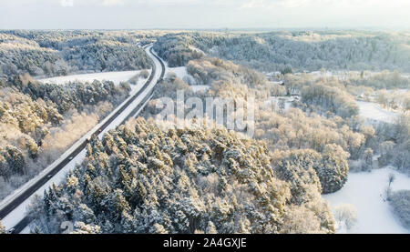 Beautiful aerial view of snow covered pine forests and a road winding among trees. Rime ice and hoar frost covering trees. Scenic winter landscape nea Stock Photo