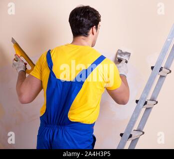 The young contractor employee applying plaster on wall Stock Photo