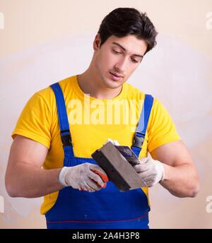 The young contractor employee applying plaster on wall Stock Photo