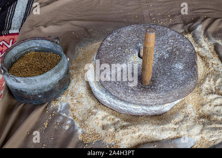 Grinding wheat by hand in stone mill Stock Photo