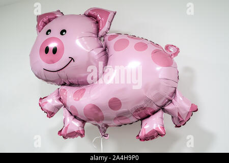 Inflatable pig shaped helium balloon on string white background lucky luck theme. Stock Photo