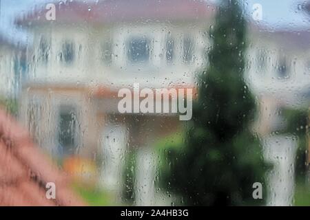 rain water droplets splash caught on glass window. caught in the rain at home. Stock Photo