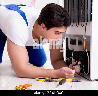 The repairman contractor repairing fridge in diy concept Stock Photo