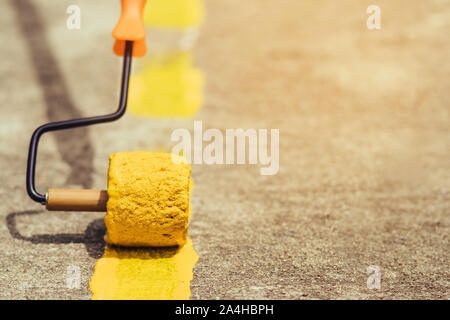 Male students use small paint rollers to paint yellow lines on the cement floor for Sepak Takraw training. Stock Photo