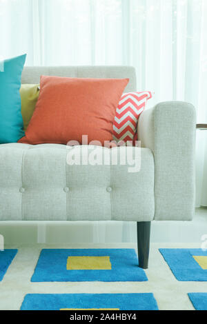 Orange and green pillows on sofa with graphic pattern carpet Stock Photo