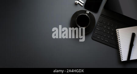 Dark modern workplace with tablet, a cup of black coffee on grey desk background Stock Photo