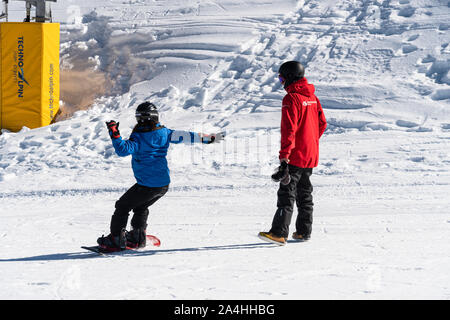 Queenstown, New Zealand - September 9 2019: A woman learn snowboarding with an instructor at the Coronet Peak ski resort in New Zealand south island Stock Photo