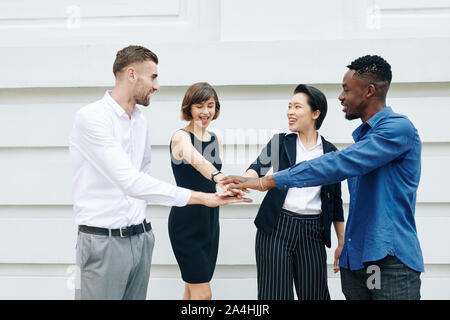 Cheerful business colleagues stacking hands to express unity and support Stock Photo
