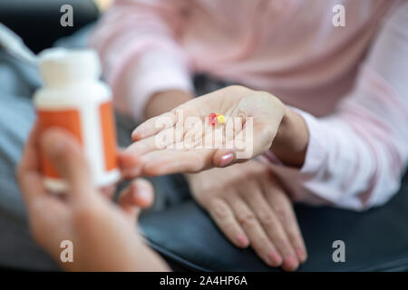 Woman wearing pink blouse having pills on palm Stock Photo