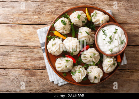 Tasty Georgian khinkali dumplings with sour cream close-up on a plate on the table. Horizontal top view from above Stock Photo
