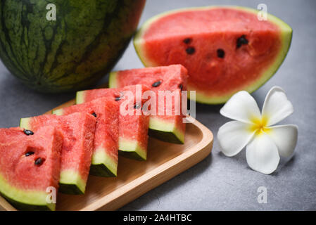 Fresh watermelon slice and white flower on the black background / watermelon tropical fruit on wood tray , selective focus Stock Photo