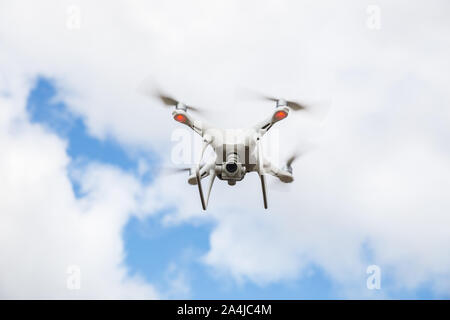 Drone quadcopter with a digital camera flies in the sky with clouds Stock Photo
