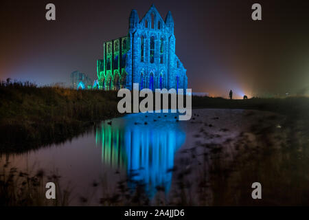 A spectacular light display illuminates the historic Whitby Abbey on October 27, 2015 in Whitby, England. The famous Benedictine abbey will be illuminated over four nights to coincide with Halloween and the popular Whitby Goth Weekend. During this time visitors to the historic English Heritage location will see the abbey bathed in spectacular light as well as experiencing the site after dark The Abbey was part of the inspiration for Bram Stoker's novel, Dracula, and sits on East Cliff in the town in a commanding position overlooking the North Sea. Stock Photo