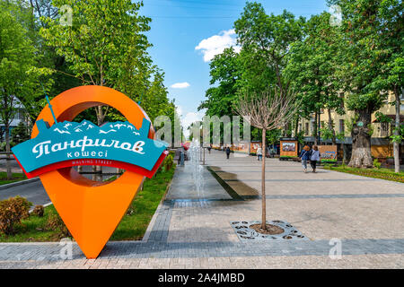 Almaty Panfilov Walking Street with Pin Pointing Road Sign and Strolling Young People on a Sunny Cloudy Blue Sky Day Stock Photo