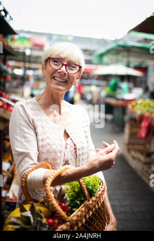 Only the best fruits and vegetables. Beautiful mature woman buying fresh food on market Stock Photo