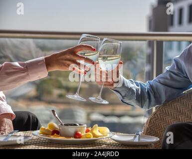 A pensioners couple enjoying a glass of white wine and a snack on the terrace of their flat Stock Photo