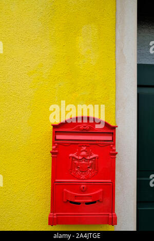 red post box hanging on a yellow wall Stock Photo