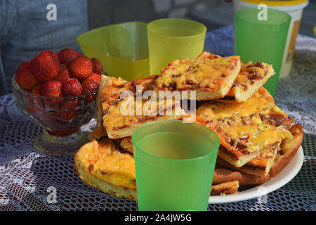 Summer party in the fresh air with pizza, strawberry and lemonade. Close up shot of slice of pizza on the plate. Stock Photo