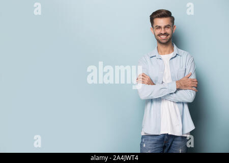 Smiling young man in glasses posing on blue background Stock Photo