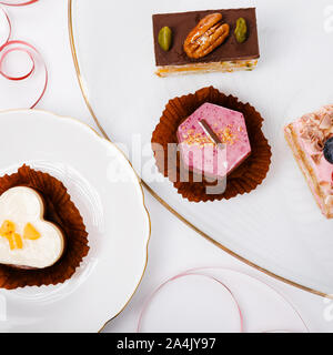 Concept for cafe or bakery with desserts, festive banner.Small cakes with different stuffing in the shape of a heart Stock Photo