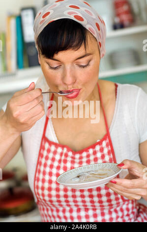 Housewife with apron tasting cooking Stock Photo