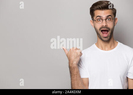 Surprised Caucasian man in glasses point at copy space Stock Photo