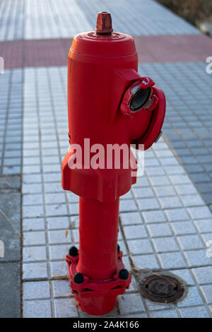 red fire hydrant installed on a city sidewalk Stock Photo