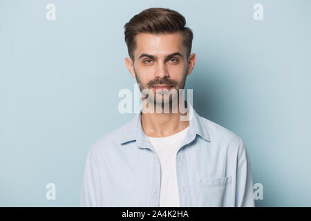 Headshot of serious caucasian young man posing on blue background Stock Photo