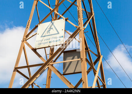 Keep your distance, Danger of death. High voltage warning sign mounted on transmission tower Stock Photo
