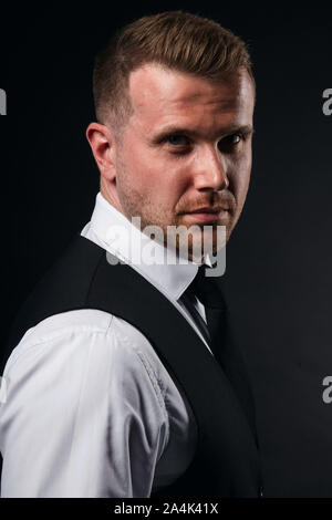 good looking young man in stylish shirt, vest looking at the camera. close up portrait, studio shot,, isolated black background Stock Photo