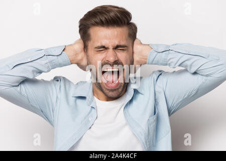 Furious man close ears scream avoiding loud noise Stock Photo