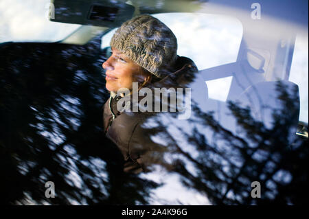 Woman in car. Reflection of forest in car window. Stock Photo