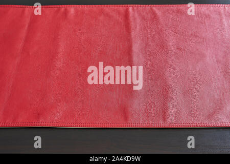 Red leather tablecloth on black wooden table, view from above Stock Photo