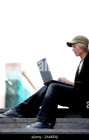 Student sitting on stairs/steps with laptop - studying Stock Photo