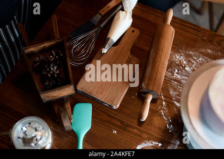Wooden cutting board , rolling pin, pastry bag on the table in the kitchen, useful tools for baking, cooking cake. Stock Photo