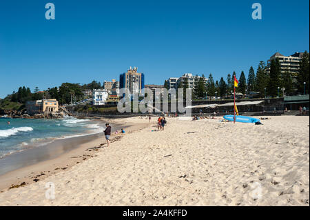 24.09.2019, Sydney, New South Wales, Australia - People in the sand under a clear blue sky on Coogee Beach with buildings in the backdrop. Stock Photo