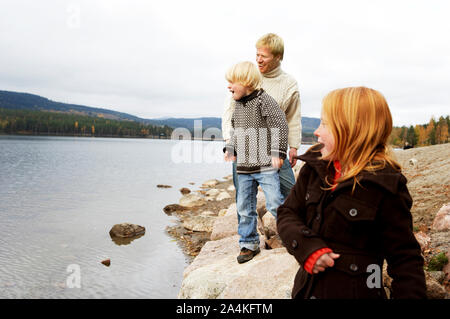 Family throwing stones into lake in Norway Stock Photo